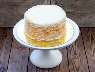 Golden and white fondant ruffle cake on rustic wooden background