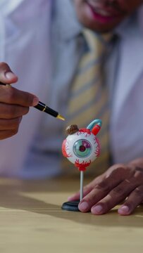 Vertical footage of doctor explaining each part of eys and ophthalmology system to patient and medical student in hospital