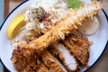 Pork cutlets and fried shrimp, garnished with lemon and vegetable salad
