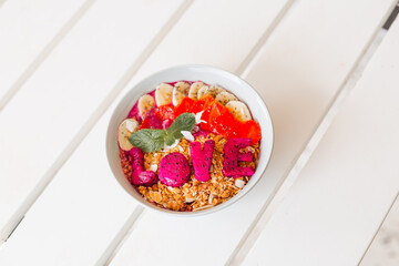 Nut muesli with fruits, berries and love. Delicious smoothie bowl with granola on a white wooden table. The concept of a delicious and healthy breakfast