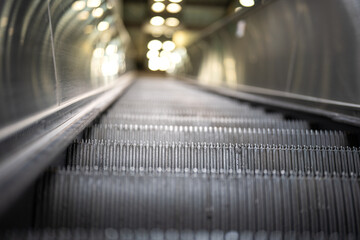 Close-up at an escalator standing panel during moving up with background of the lighting bokeh. The...