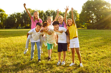 Happy children friends standing together outdoors, having fun and smiling in the park on holidays enjoying spending time in a summer camp. Portrait of a kids looking at camera having weekend activity