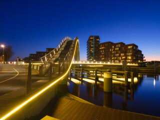A bridge in the city at night. City lights. The Galaxy Bridge, Purmerend, Netherlands. The bridge on the blue sky background during the blue hour. Architecture and design. - 745912582
