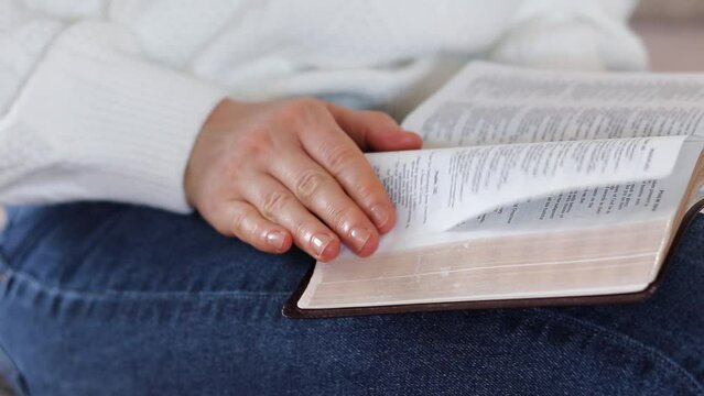 Person reading and studying from open holy bible book. Close-up. Selective focus.