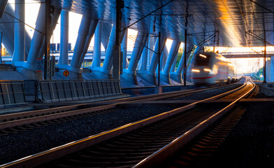 Fast train arriving at the station of Frankfurt Airport backlit by low sun. Panoramic view from...
