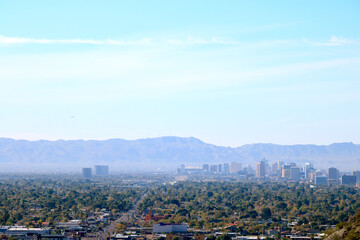 Fototapeta na wymiar High rise buildings of Phoenix downtown in the Valley of the Sun with a backdrop of South Mountains as seen from North Mountain Park hiking trails on a sunny Spring morning, Arizona