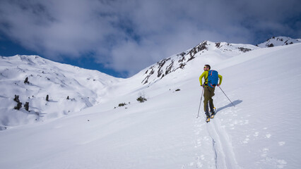 Fototapeta na wymiar Man on mountain ski tour in the snow on sunny day, looking at the winter panorama around.