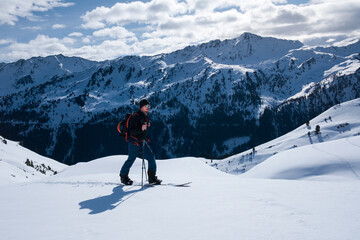 Man on mountain ski tour in the snow on sunny day, winter mountain panorama in background. - 745922320