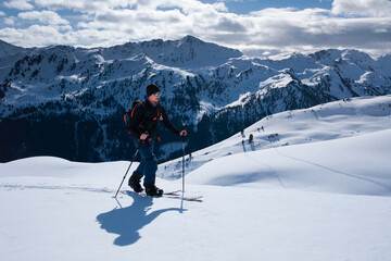 Man on mountain ski tour in the snow on sunny day, winter mountain panorama in background. - 745922521