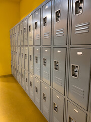 Rows of Gray School Lockers Lined up Against a Yellow Wall