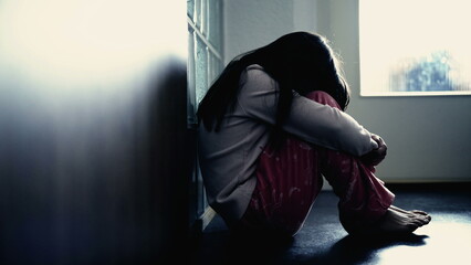 Sad child suffering from depression sitting alone in corridor feeling loneliness. Scared fearful...