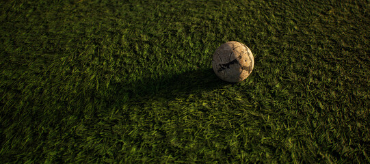 Worn old football on artificial grass. Lit by sunlight. - 745930940
