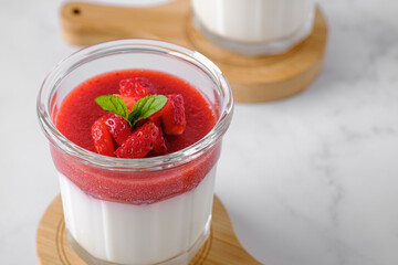 Glass of traditional italian dessert panna cotta with strawberries closeup. Gluten-free vegetarian...