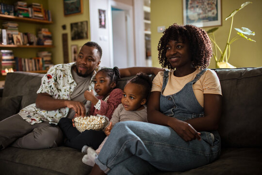 African American family watching a movie on the sofa at home