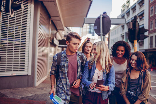 Diverse group of friends walking in the city with a map