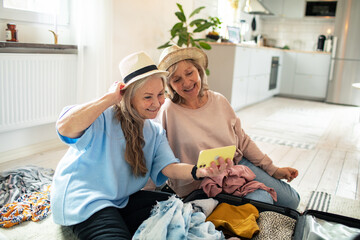 Senior lesbian couple packing clothes for trip at home