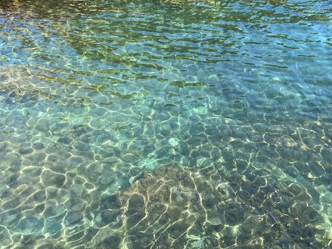 Sea water transparent light green blue surface ripples.