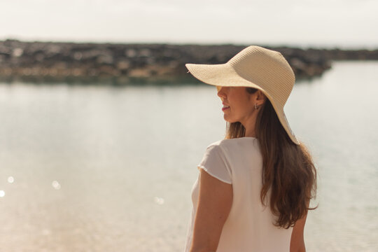 Idyllic portrait image of a woman with a sideways hat on a beach.dng