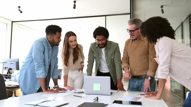 A panoramic view of a motivated team intensely focused on a computer screen, capturing the essence of a strategic work session in a contemporary, light-filled office. Diverse work group brainstorming
