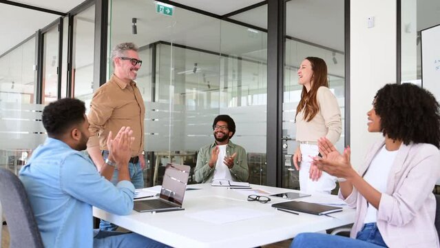 In a spirited office atmosphere, colleagues share a high-five, celebrating a successful moment with clapping and smiles, highlighting the camaraderie and success within the team