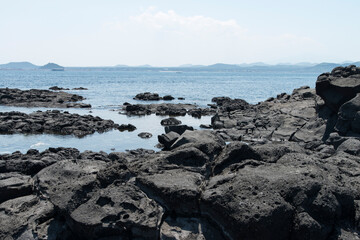 Fototapeta na wymiar The beach of black rocks at the island seaside