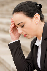 Young female office worker with her head in her hand looking upset and distraught. 