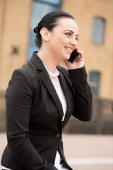 Portrait of a smiling young office worker, holding a mobile phone to her ear and listening.