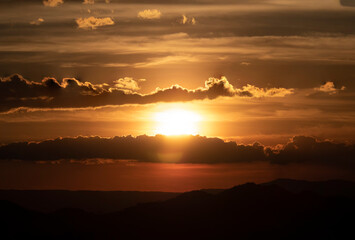 The stunning view from a tourist's standpoint as they go down a hill on a foggy trail with a hill and a background of a golden sky in Forest Park, Thailand. Bird's eye view. Aerial view. Rainforest