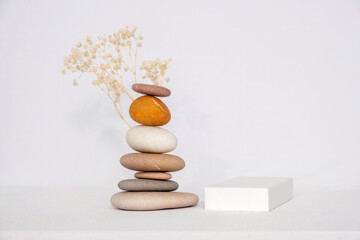 Pyramid of pebbles, dried sprig and podium. Isolated on white background.