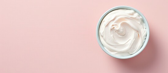 A bowl filled with whipped cream sits on a pastel pink background, creating a striking contrast. The fluffy cream looks light and airy against the solid backdrop. - Powered by Adobe