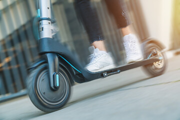 Cropped image of unrecognizable modern girl rides on high tech e-scooter. Ecologically sound clean...