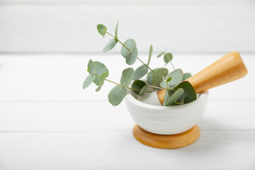 Eucalyptus leaves and mortar on a wooden background.Spa concept.Ingredients for alternative medicine and natural cosmetics. A bottle of essential oil and a bunch of eucalyptus. Organic skin care 