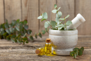 Eucalyptus leaves and mortar on a wooden background.Spa concept.Ingredients for alternative medicine and natural cosmetics. A bottle of essential oil and a bunch of eucalyptus. Organic skin care 