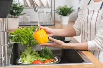 Close up hand of asian young housekeeper woman, washing sweet pepper, yellow paprika, vegetables...