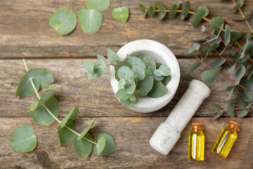 Eucalyptus leaves and mortar on a wooden background.Spa concept.Ingredients for alternative medicine and natural cosmetics. A bottle of essential oil and a bunch of eucalyptus. Organic skin care 