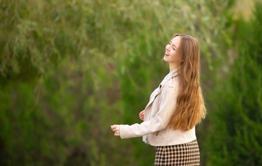 A young smiling girl walking in an autumn park in a good mood. Teenage girl, portrait against a background of nature. Fashion style trend.