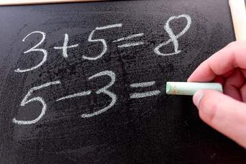 closeup teacher write simple math addition of chalkboard, primary school