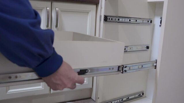 installing a drawer in the kitchen cabinet, a carpenter assembles kitchen furniture in an apartment