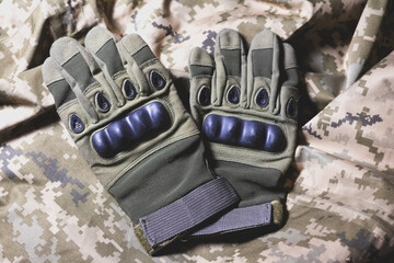 Tactical military gloves on the khaki camouflage uniform. Soldier ammunition.