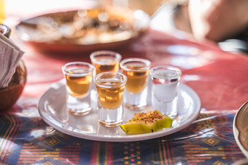 Mezcales, a typical Mexican drink served in glass horses, natural and combined with plum, accompanied by a star fruit with chili powder.