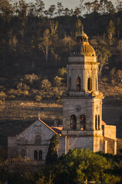 Main church of the Municipality of Charo Michoacan, with the sunlight hitting it laterally at sunset, with the mountains behind it.