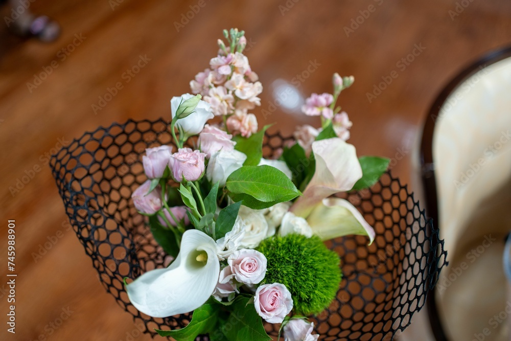 Canvas Prints small vase of flowers inside a wire basket on top of a wooden table