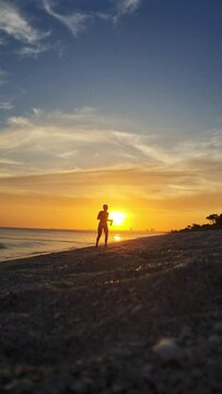 Joven mujer camina en la playa con el atardecer de fondo en playa Caracol, Chame panama.