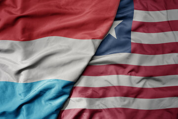 Fototapeta premium big waving national colorful flag of liberia and national flag of luxembourg .