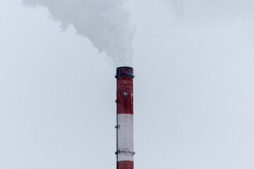 Pipe of a thermal power plant expels a dramatic plume of steam into the overcast sky, highlighting...