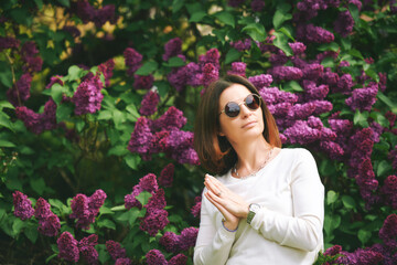 Spring portrait of pretty mature woman posing with lilac flowers on background - 745993585