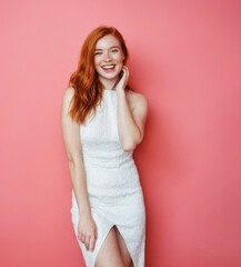 Naklejka premium Young ginger laughing woman in white dress against orange solid background