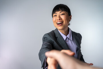 Happy Asian businesswoman doing handshake with man at office. Businesswomen Shaking Hands Isolated on Grey Background. Happy businesswoman shaking hand with businessman after interview at office