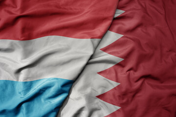 big waving national colorful flag of bahrain and national flag of luxembourg .
