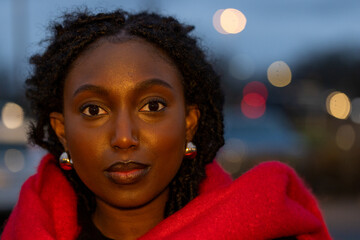 This portrait captivates with a young woman's direct stare into the lens, her face illuminated by...